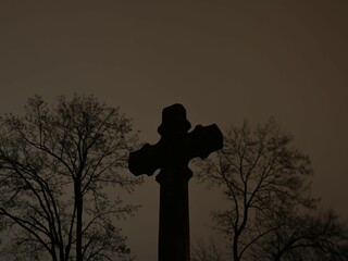 Stary krzyż na tle nocnego zachmurzonego nieba, opuszczony cmentarz 