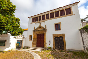 A historic building with a whitewashed facade and a prominent stone doorway, surrounded by a...