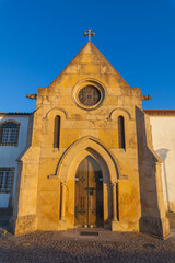 A historic church with a stone facade and a bell tower, bathed in the warm glow of the setting sun