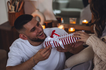 Happy loving young beautiful couple exchanging gift boxes for Christmas, new year or saint...