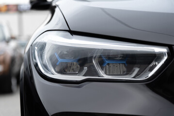 Fototapeta premium black car headlight, close up view, car dealing and manufacturing, cropped car image