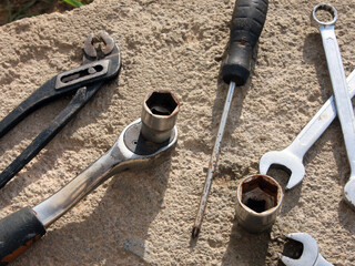 Automotive tools: ratchet, captive horn wrenches, screwdrivers, pliers, tongs on a concrete surface background. Garage and workshop. Automotive mechanics, engineering, manufacturing, industry