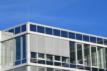 Modern minimalist facade of an office building, blue sky, white gray facade