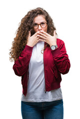 Beautiful brunette curly hair young girl wearing jacket and glasses over isolated background shocked covering mouth with hands for mistake. Secret concept.