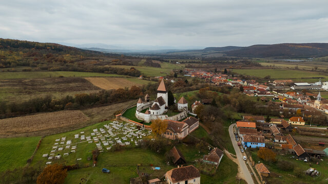 A stock photo of the Hosman Fortified Church in Romania during autumn showcases the beauty of this medieval structure amidst the vibrant colors of fall. 