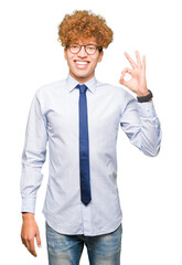 Young handsome business man with afro wearing glasses smiling positive doing ok sign with hand and fingers. Successful expression.