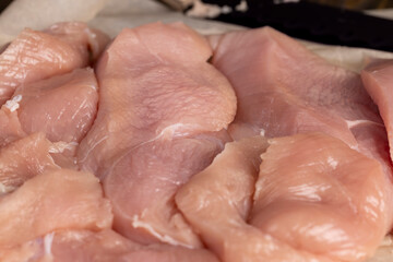 a lot of a piece of fresh chicken meat in close-up lies on paper
