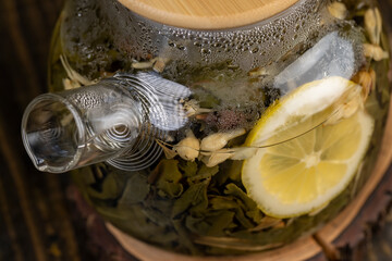 making green tea in a glass teapot with lemon and mint