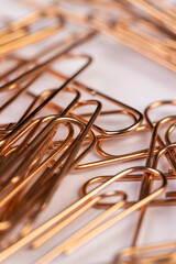 large-sized copper paper clips lie on white blank paper