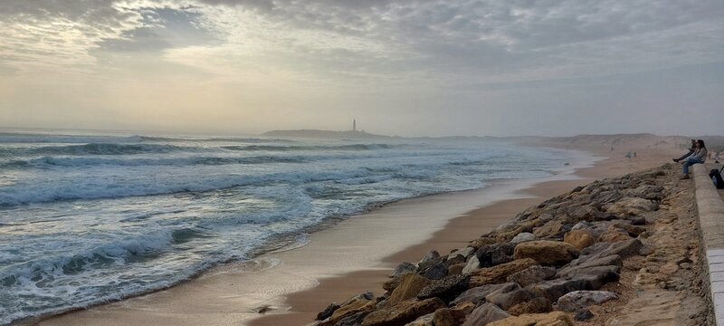 Big wave Saturday at Playa Ca&ntilde;os de Meca Beach, Spain, ocean spray creating a cover of mist turning the afternoon sun into a diffuse, surreal shroud of light obscuring Trafalgar lighthouse in the back