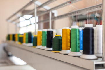 Colorful spools of thread mounted on an embroidery machine in action. Focus on embroidery, small...