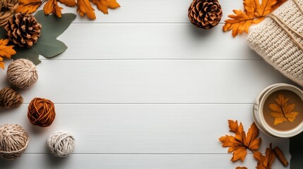 Cozy autumn arrangement featuring colorful leaves, pinecones, yarn balls, and a warm beverage on white wood