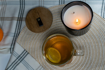 Overhead view of a cup of tea with lemon and a burning candle, emphasizing a cozy and peaceful atmosphere.