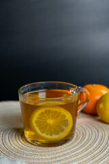 A cup of tea with lemon and a tangerine in the background, emphasizing warmth and coziness.
