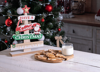 gingerbread cookies and a glass of milk on a background of a Christmas tree