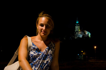 The Castle of Nitra at night from the river and a young woman