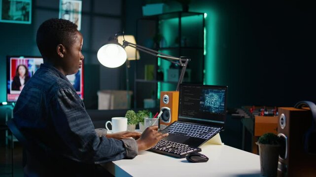AI professional in home office using laptop to write programming language code. Artificial intelligence engineer working from home using notebook device to build application, camera B