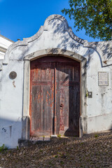 A weathered wooden door framed by a decorative stone archway, leading to a hidden courtyard