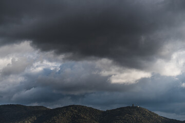 View of hills under rainy clouds