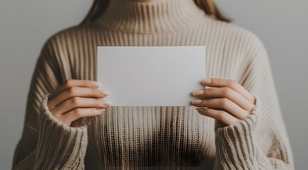 Naklejka premium Woman In Beige Sweater Holding Blank White Card