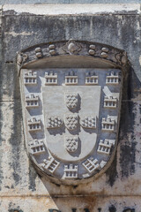 A close-up view of the Coat of Arms of Portugal, carved in stone and displayed on a historic building