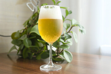 A full glass of beer with a frothy head on top, standing on a table