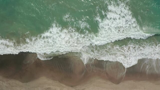 Aerial of waves crashing and surfer riding wave