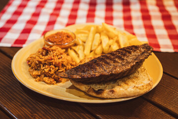A juicy stuffed burger packed with cheese, accompanied by crispy fries, rice, and a tangy sauce, perfect for a filling meal.