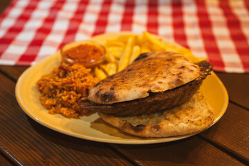 A delicious stuffed burger filled with melted cheese served alongside golden fries, seasoned rice,...