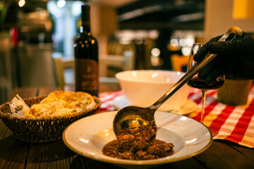 A close-up of a ladle pouring rich, flavorful goulash into a bowl, capturing the warmth of home-style cooking.