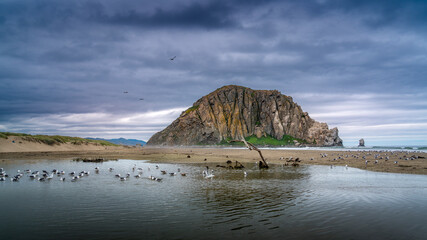 Dark clouds hanging over Morro Bay create a dramatic scene, as the massive volcanic plug Morro Rock, towers 580 feet above the Pacific Ocean, is standing proud below the dark skies.