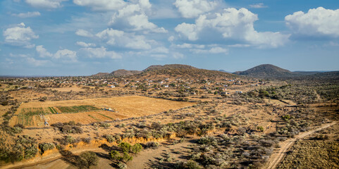aerial african landscape savannah, with acacia trees and bush, near a village with agricultural parcel of land