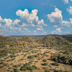 aerial view african landscape, mountain range and hills, savannah plain with acacia trees and bush , sunny afternoon