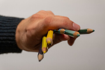 Hand pointing sharp end of colored pencils towards the camera