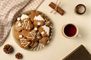 Coziness composition with gingerbread, cup of tea and book on beige background. Christmas concept. Flat lay, top view.