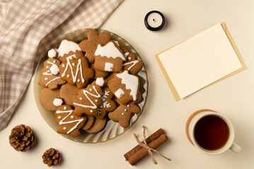 Coziness composition with gingerbread, cup of tea and blank card on beige background. Christmas concept. Flat lay, top view.