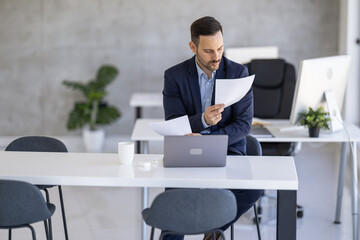 Focused Businessman Reviewing Documents in a Modern Office