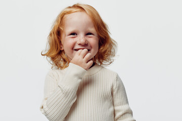 Happy little girl with red hair smiling and covering mouth with hand, beauty and joy in childhood