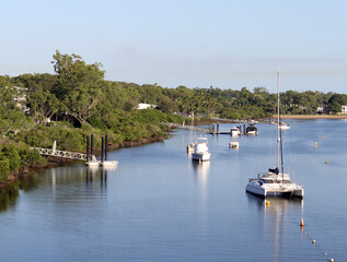 Boats moored in the Boyne River under a clear blue sky at Tannum Sands in Queensland, Australia