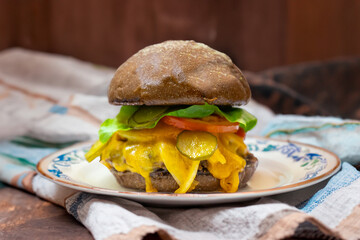 Traditional rustic burger sandwich with cheddar cheese, vegetables and Australian bread in creative photography and cozy village setting