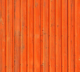 A close-up view of a textured, vibrant orange wooden wall.