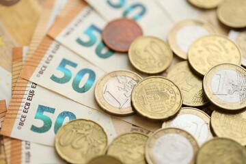Many cent coins of euro currency lies on many fifty euro bills banknotes
