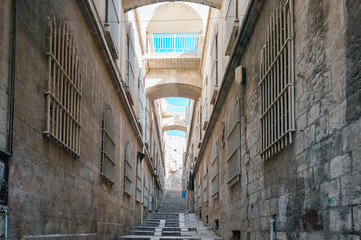 A narrow alleyway with a blue archway and a balcony