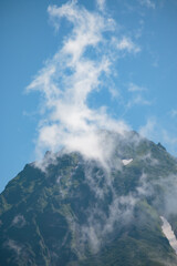 Cloud mist rising from the top of a rocky mountain peak in summer