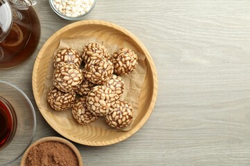 Tasty chocolate puffed rice balls served with tea on wooden table, flat lay. Space for text