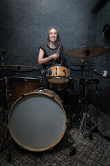 Smiling female drummer performing on drum set in professional soundproof studio. Vibrant scene emphasizes energy, creativity, and joy of live music creation, vertical image