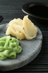 Hot wasabi paste, soy sauce and ginger on black textured table, closeup