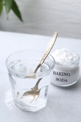 Glass of water and baking soda on white table. Space for text