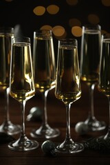 Champagne in glasses and decor on wooden table against blurred Christmas lights. Bokeh effect