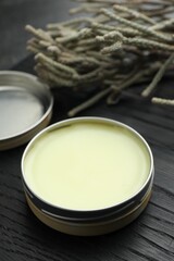 Natural solid perfume and plant on black wooden table, closeup